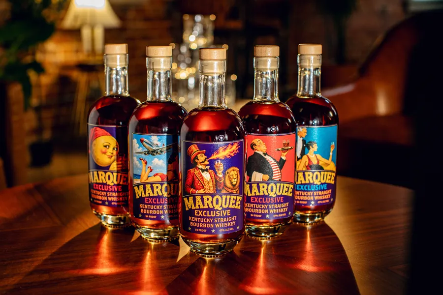Five Marquee Exclusive bottles on a lamp-lit bar table